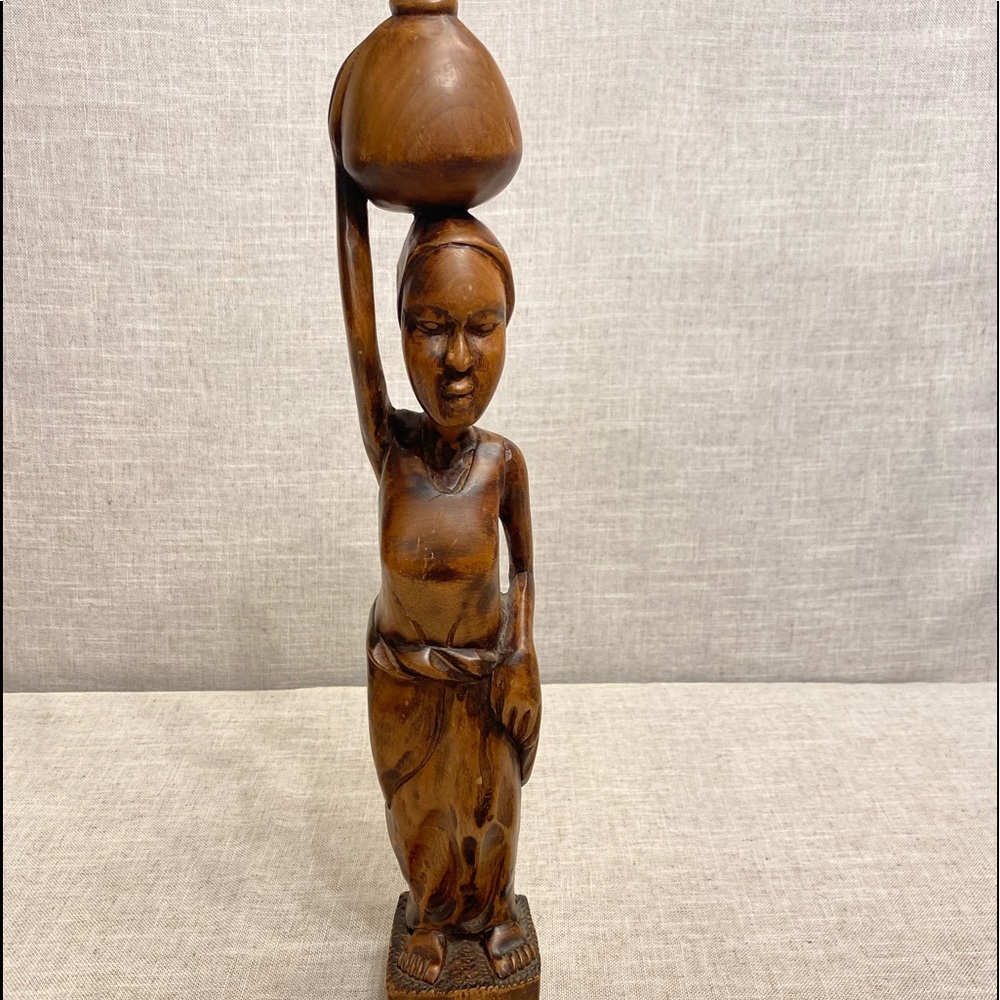 Hand carved wooden native woman carrying jug on head.